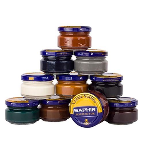 A collection of Saphir shoe polish jars in various colors, stacked in a pyramid shape.