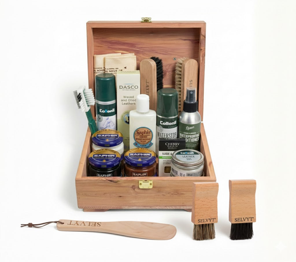 Shoe care kit with various items in a wooden box on a white background