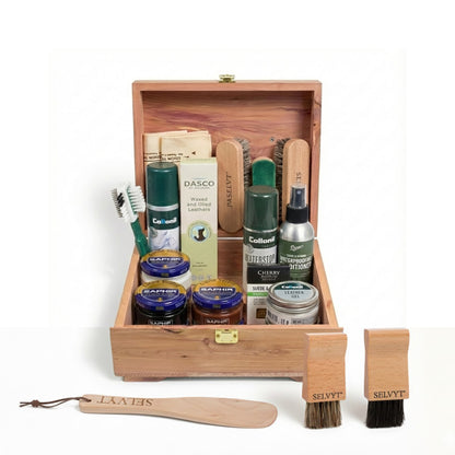 Shoe care kit with various items in a wooden box on a white background